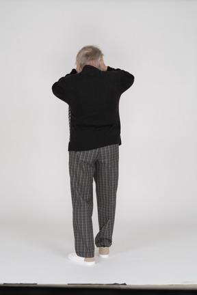 Rear view of old man holding head