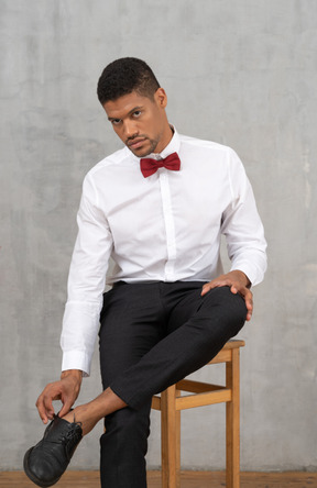 Young man on a chair adjusting his shoes