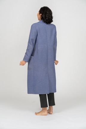 握りこぶしで立っているコートを着た女性の背面図
