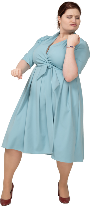 Вид спереди женщины в синем платье, притворяющейся, что она играет на скрипке