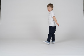 Vista lateral de un niño caminando con los brazos a los lados