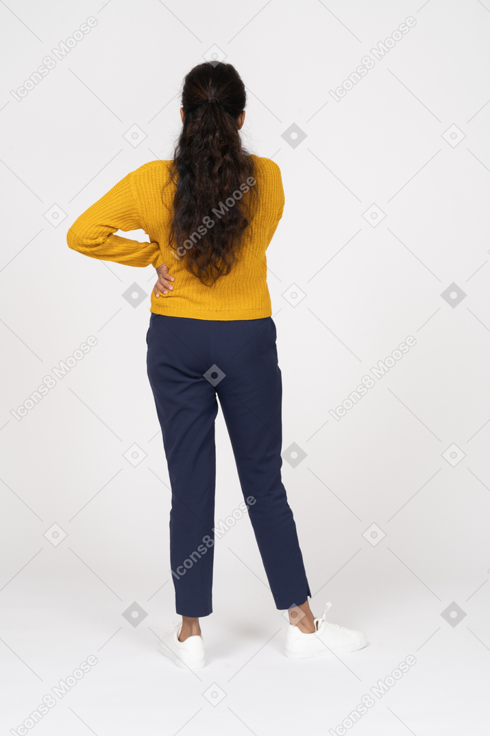 一个穿着休闲服、手放在臀部摆姿势的女孩的后视图
