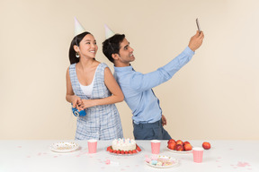 Joven pareja interracial haciendo una selfie mientras celebra cumpleaños