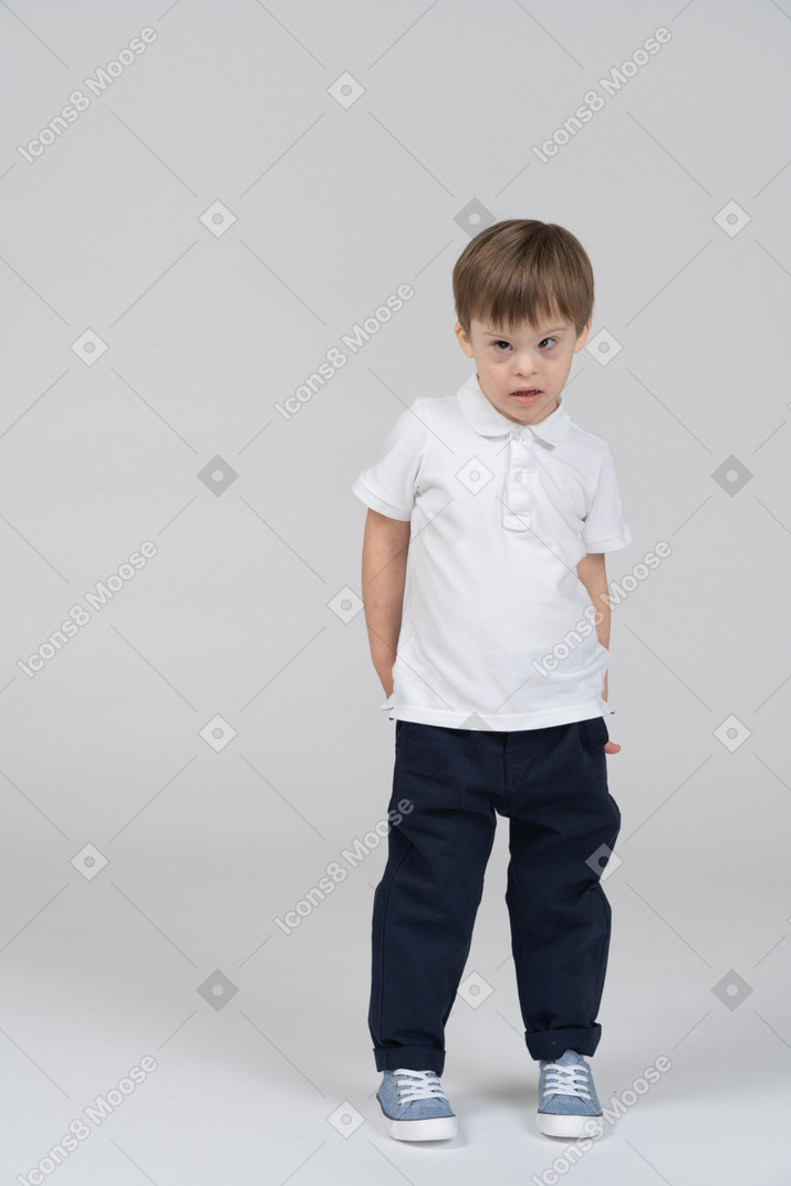 Little boy standing with hands behind back