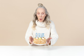 Alte frau bläst die kerzen auf kuchen zu ihrem hundertfünften geburtstag aus