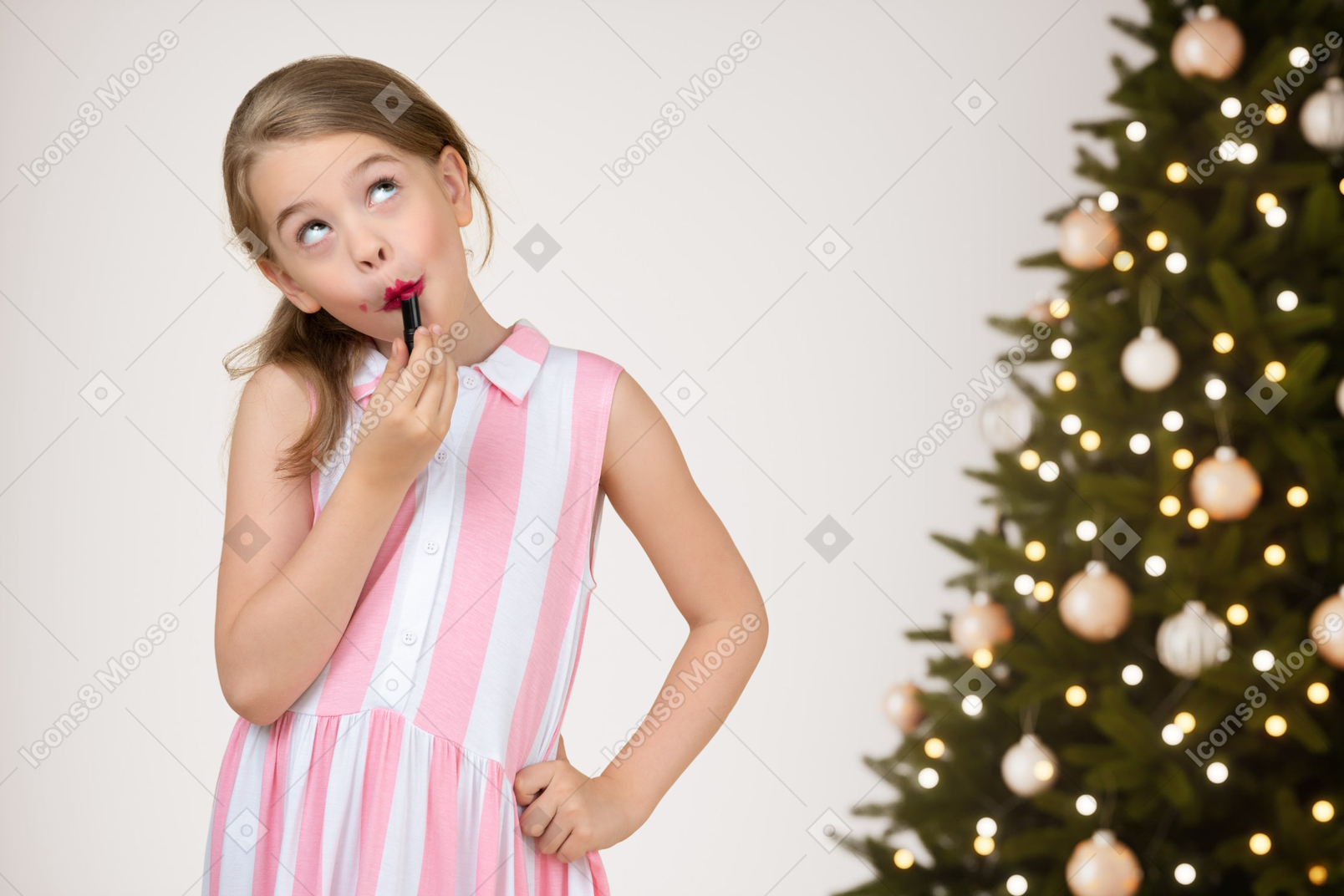 Young girl putting lipstick on her lips before christmas party