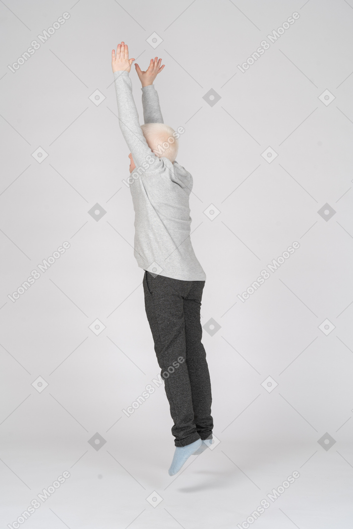 Side view of a boy jumping with hands in the air
