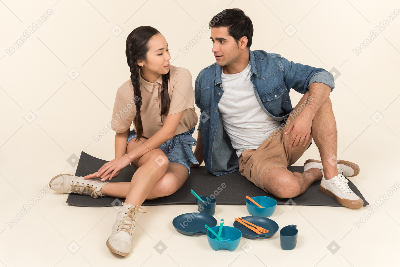 Interracial couple sitting on karimat near dishes