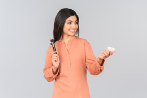 Indian woman holding face powder and powder brush