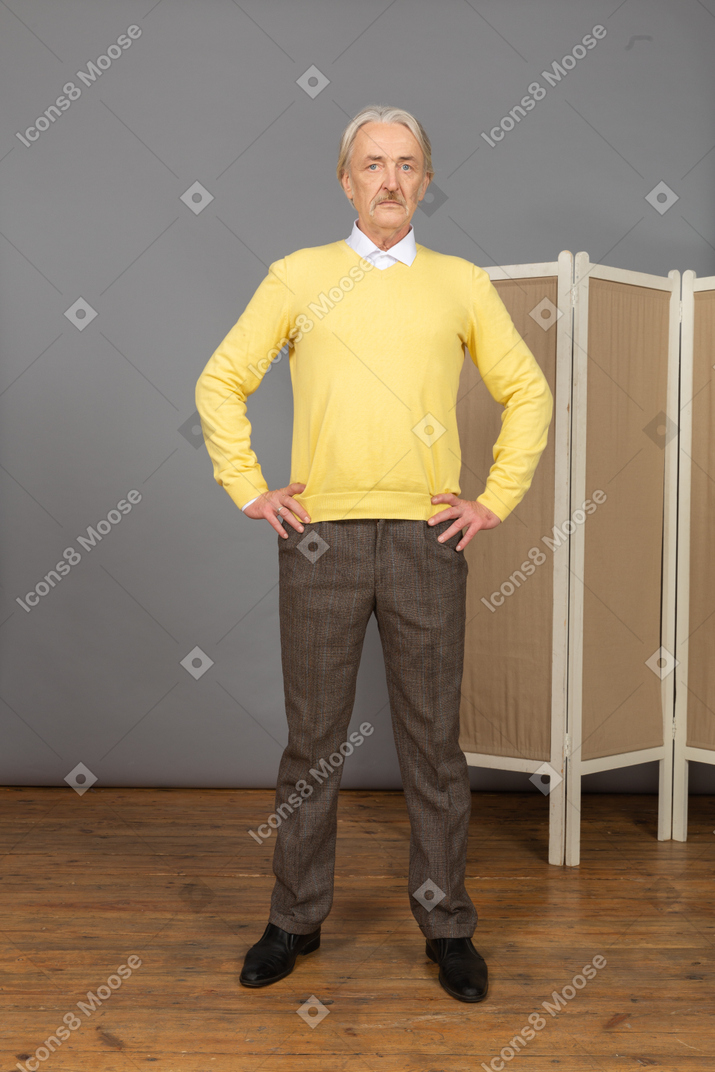 Vista laterale di un uomo anziano serio che mette le mani sui fianchi