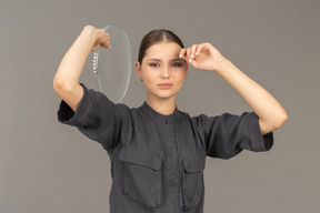 Front view of a young woman in a jumpsuit holding glass plate