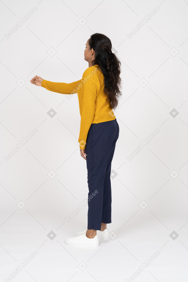 Side view of a girl in casual clothes standing with extended arm