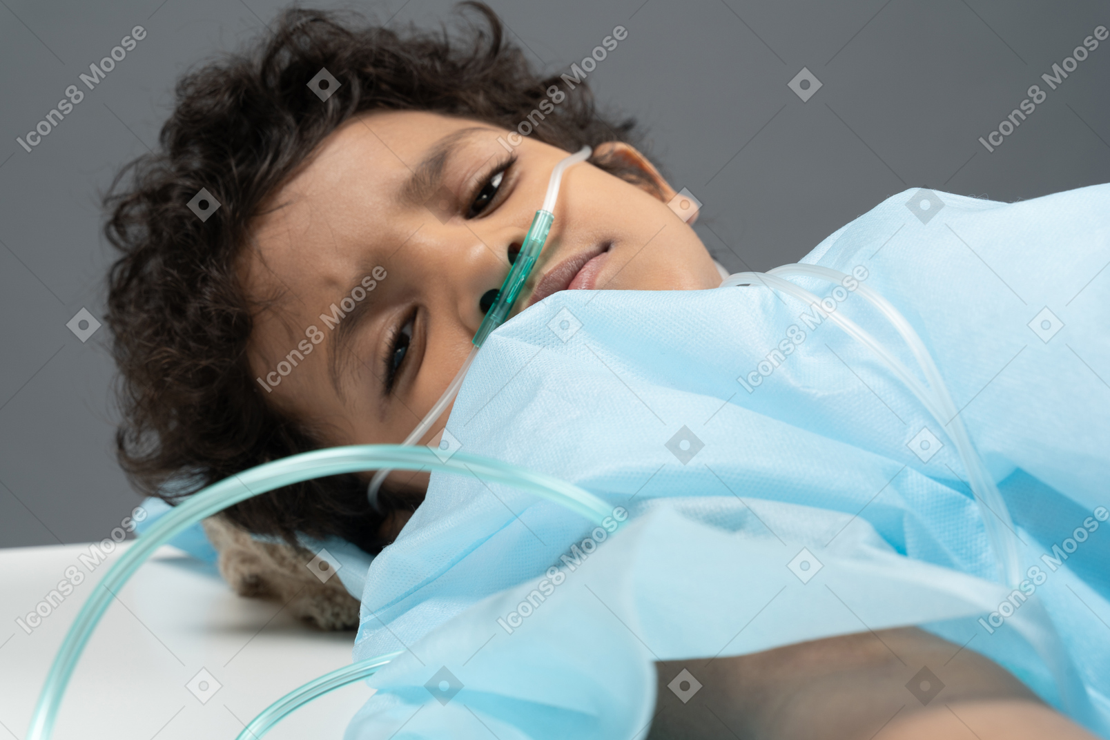 Ребенок с носовой канюлей смотрит в камеру