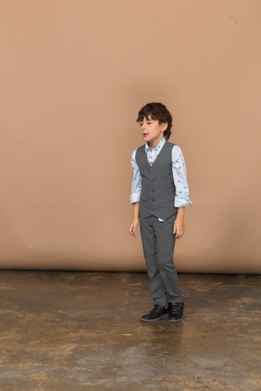 Vista frontal de un niño en traje parado quieto