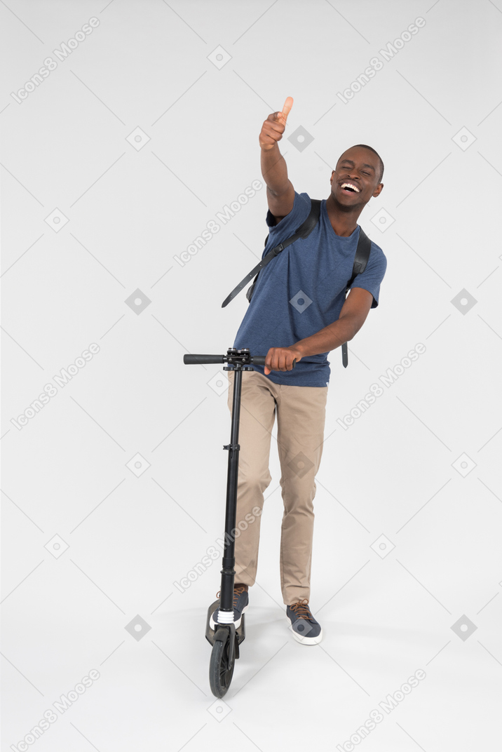 Smiling black male using scooter and showing thumb up