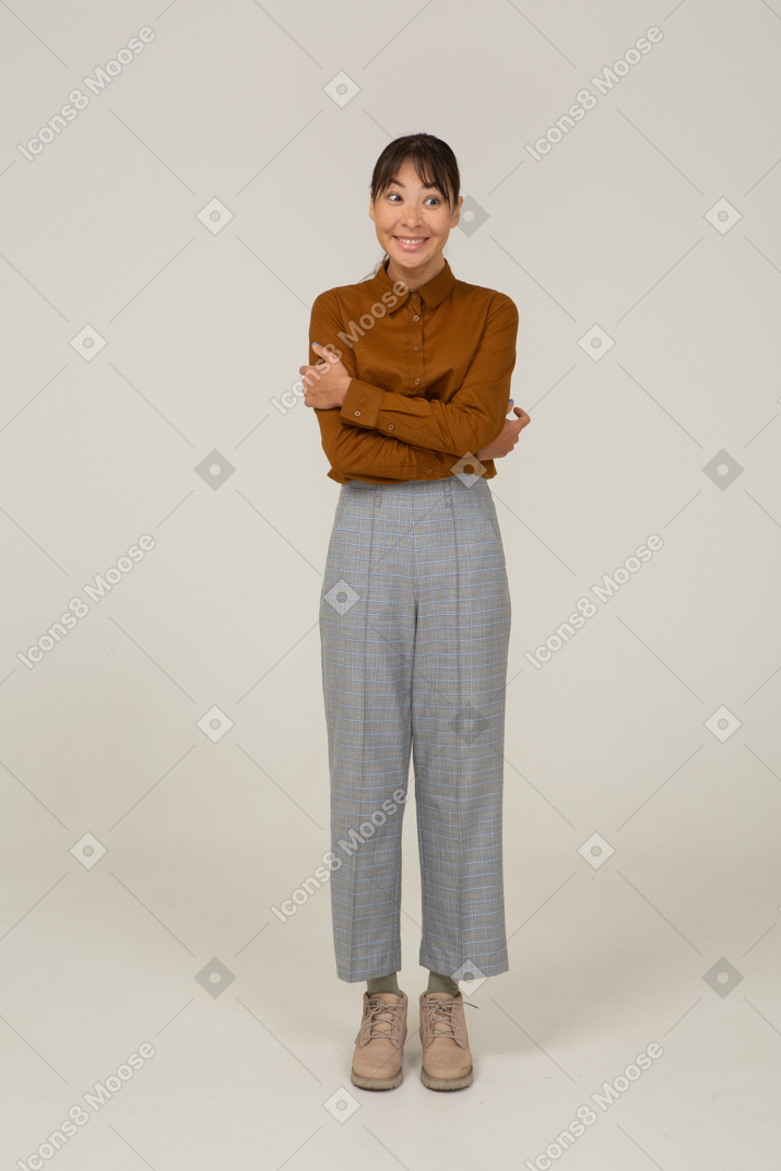 一个微笑的年轻亚洲女性的正面图马裤和衬衫交叉双臂