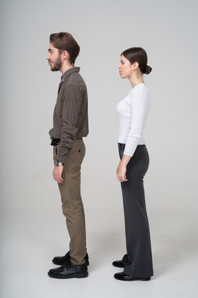 Vista lateral de um jovem casal confuso com uma careta em roupas de escritório