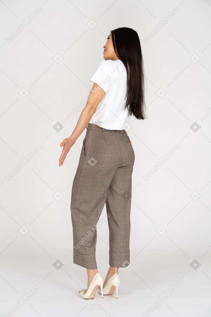 Three-quarter back view of a young lady in breeches and t-shirt outspreading her hands
