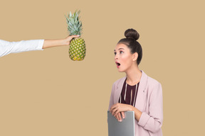 Erstaunt junge frau ananas betrachten