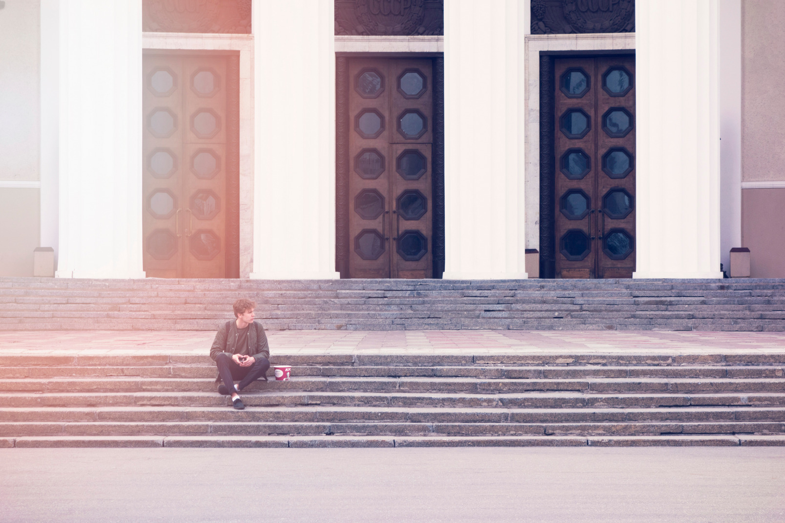 Young guy sits on stairs in front of a building