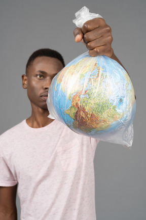 A young man holding a white plastic with the earth globe