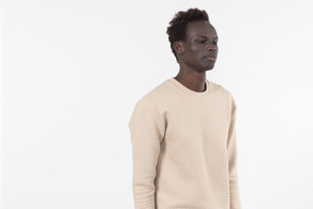 A young black man in a grey sweater standing alone on the white background