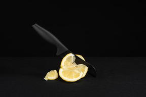 暗闇の中でレモンを切る黒いナイフ