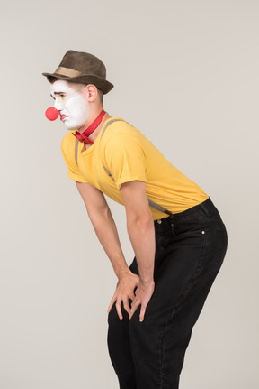 Sad male clown standing with hands behind the back