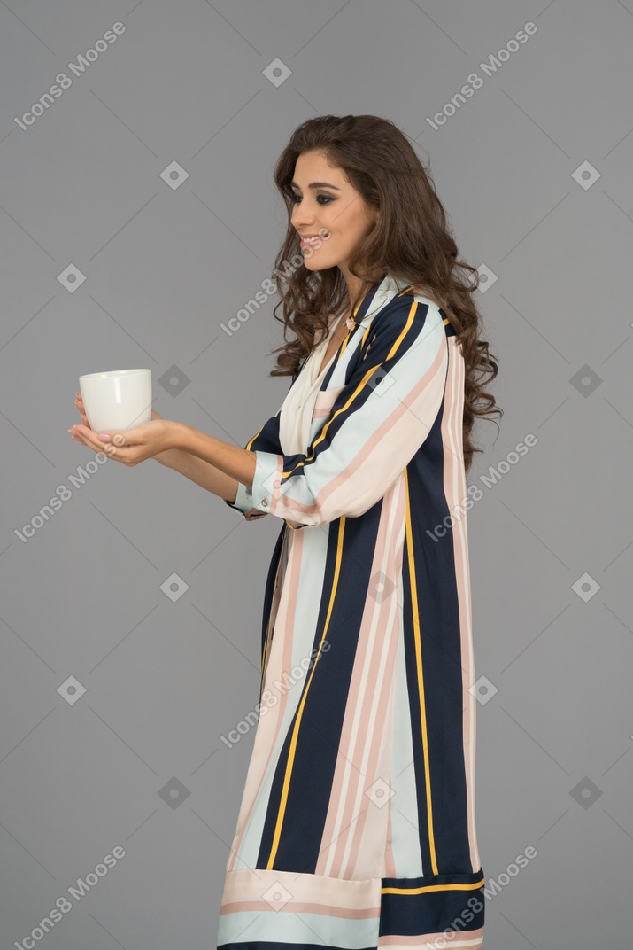 Cheerful young arab woman holding white cup with both hands