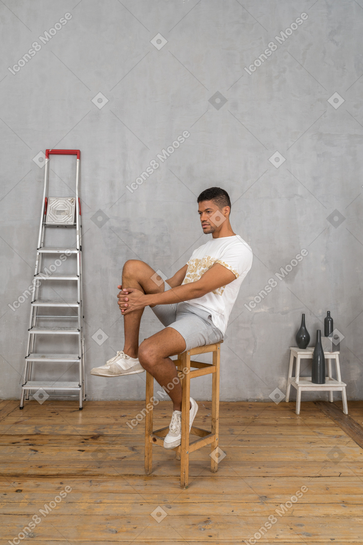 Homem sentado na cadeira e abraçando o joelho