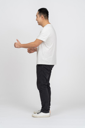 Side view of a happy man in casual clothes showing thumb up