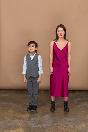 Vista frontal de um menino e uma mulher sorrindo com um vestido vermelho