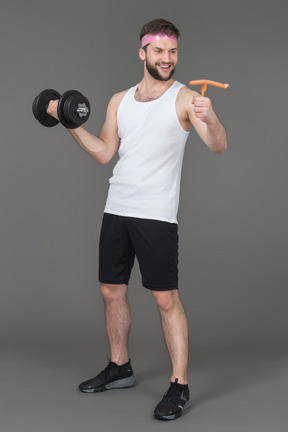 A cheerful young man working out with a dumbbell