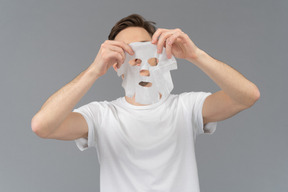 Vista frontal de um jovem pronto para colocar uma máscara facial