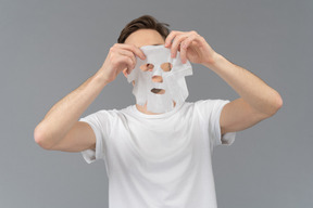 Vue de face d'un jeune homme prêt à mettre un masque facial