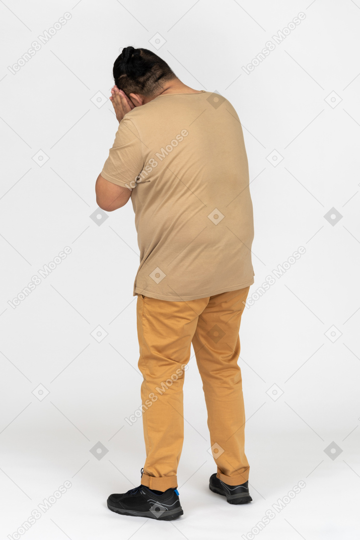 Plus size asian man standing back to camera with his hands pressed together next to head