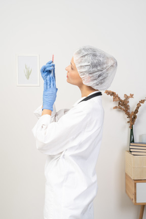 Side view of a young female doctor holding a syringe