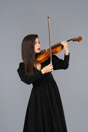 Close-up de uma jovem de vestido preto tocando violino