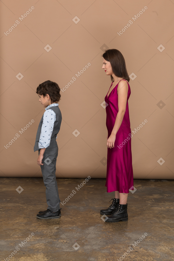 Mujer decepcionada en vestido rojo con un niño de pie en el perfil