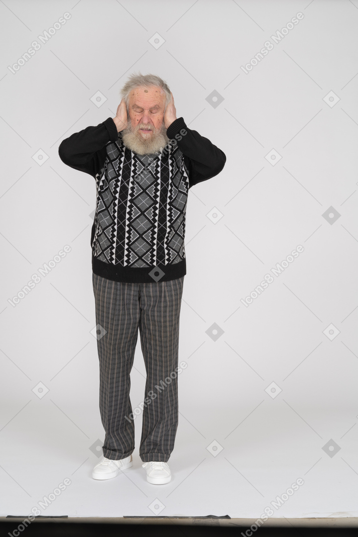 Old man with eyes closed covering ears