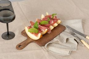 Antipasto con melone e prosciutto freschi serviti su una tavola di legno