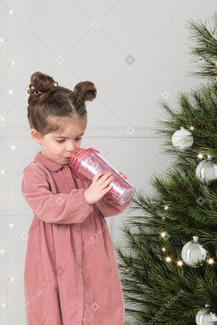 A little girl standing next to a christmas tree