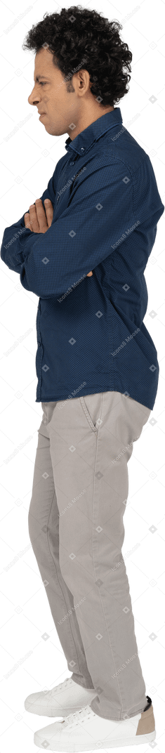Seitenansicht eines mannes in freizeitkleidung, der mit verschränkten armen steht