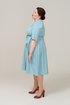 Vista laterale di una donna in abito blu che fa smorfie
