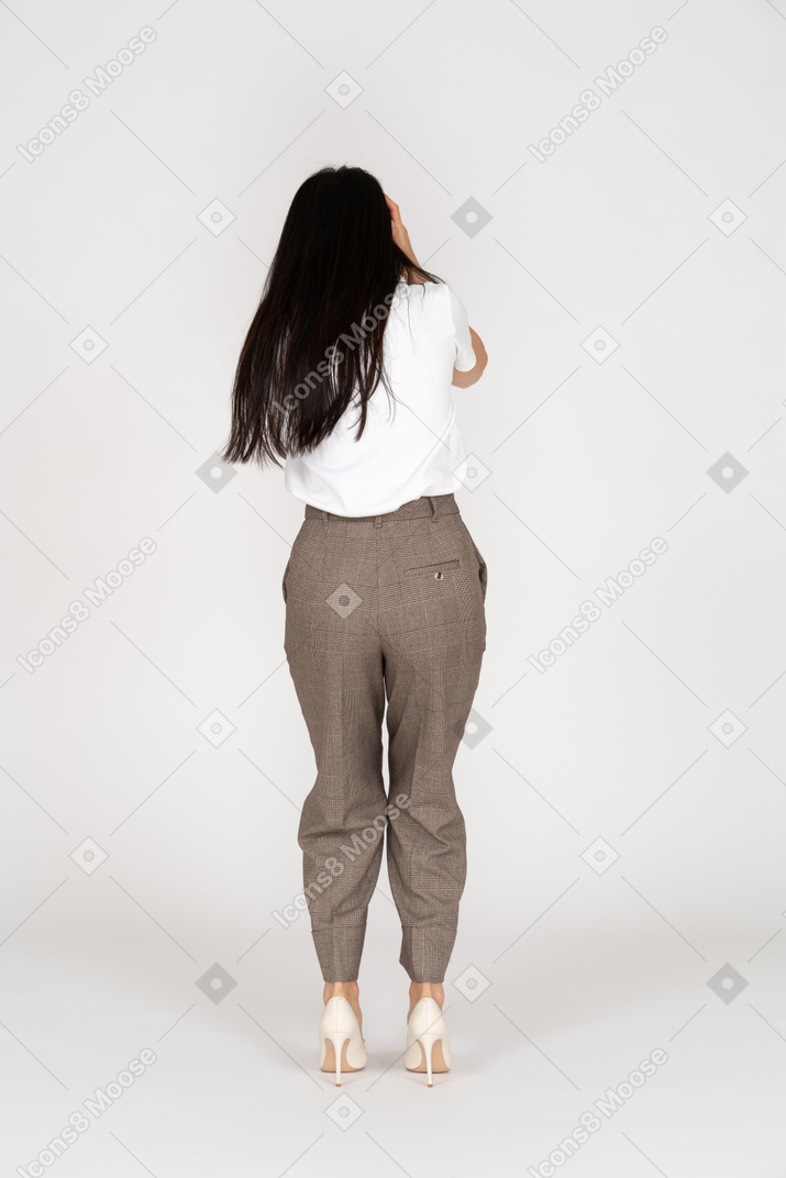 Vista posterior de una mujer joven asustada en calzones tocando su cabeza