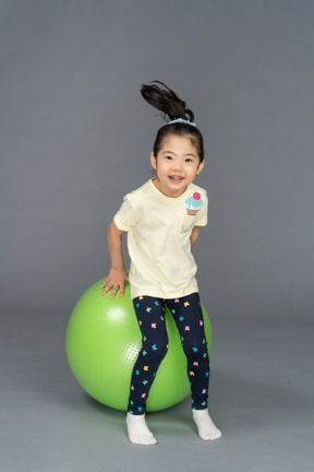 Bambina che salta su un fitball verde