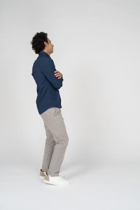 Vista lateral de um homem com roupas casuais em pé com os braços cruzados