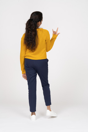 Rear view of a girl in casual clothes making rock gesture