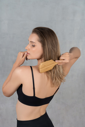 Ritratto di una giovane donna che si spazzola i capelli e si tocca il labbro