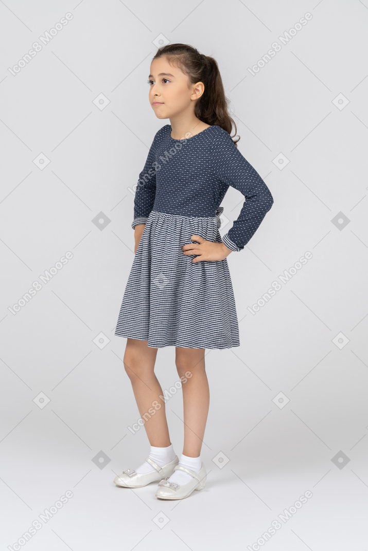 Vista de tres cuartos de una niña con las manos en las caderas